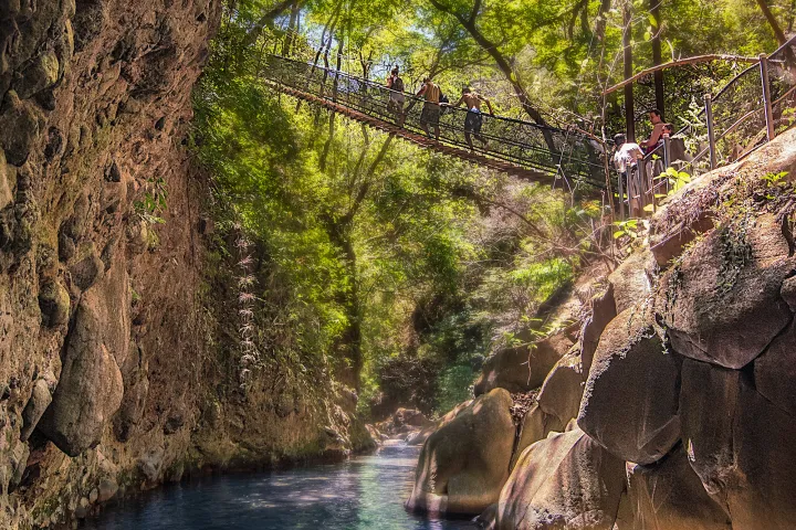 boys crossing bridge over waterfall