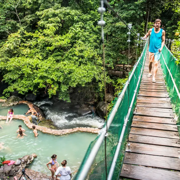 man crossing bridge over hot springs
