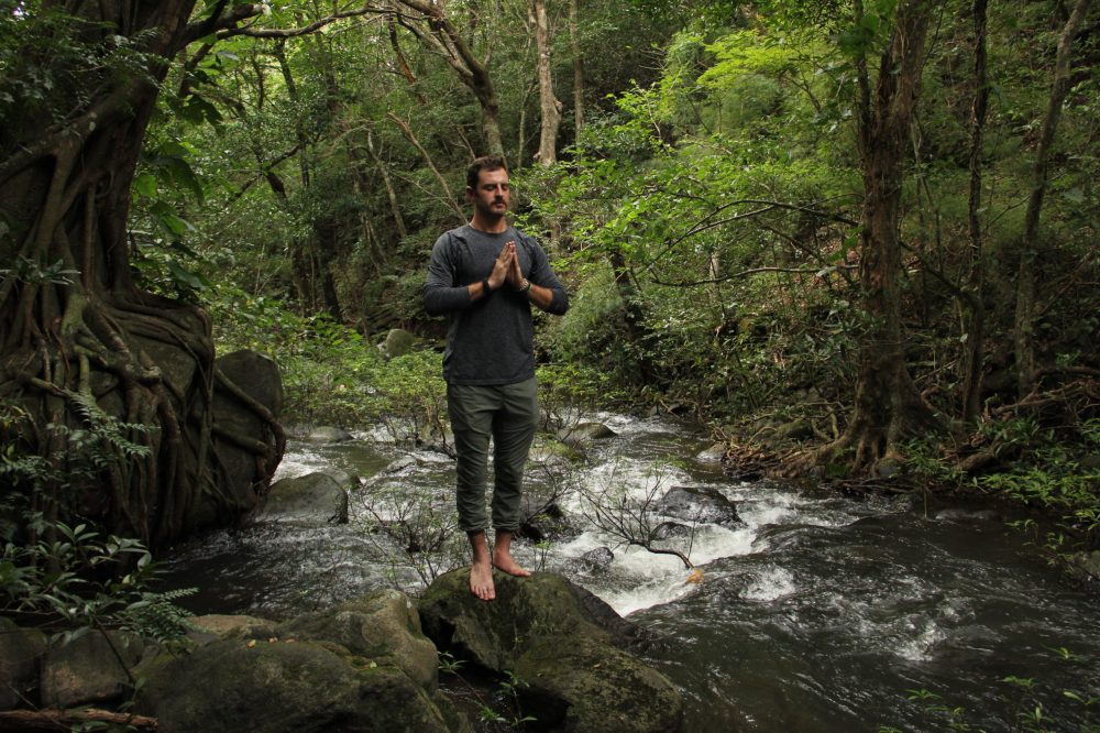 a man standing next to a tree in a forest