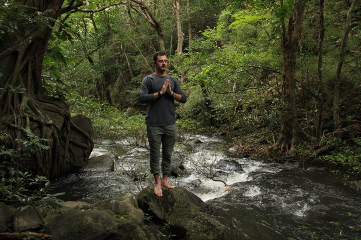 a man standing next to a tree in a forest