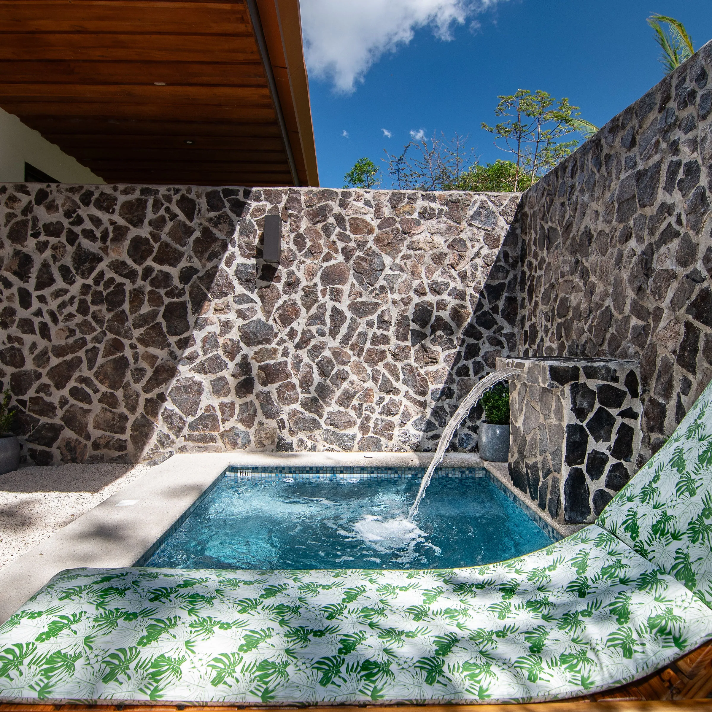 a giraffe sitting down in front of a brick wall