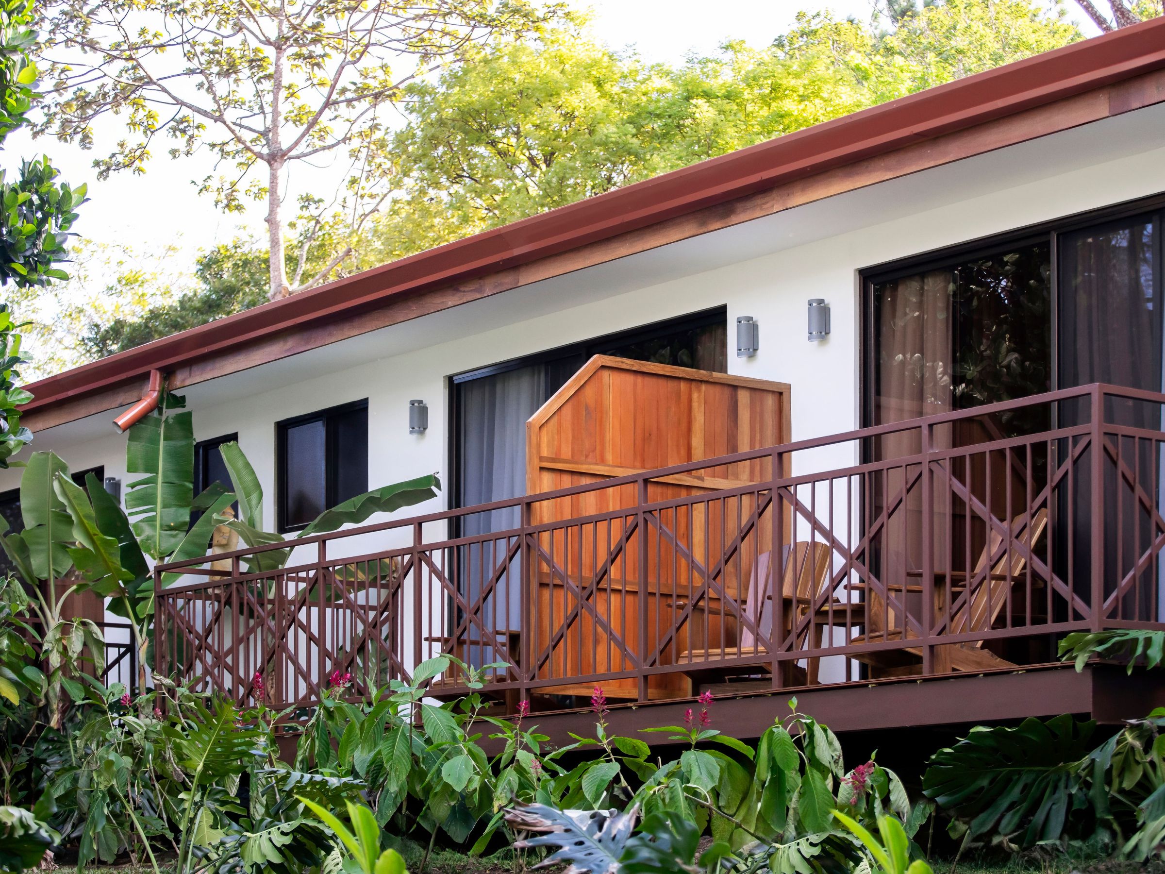 Exterior view of a house with a wooden deck and tropical plants.