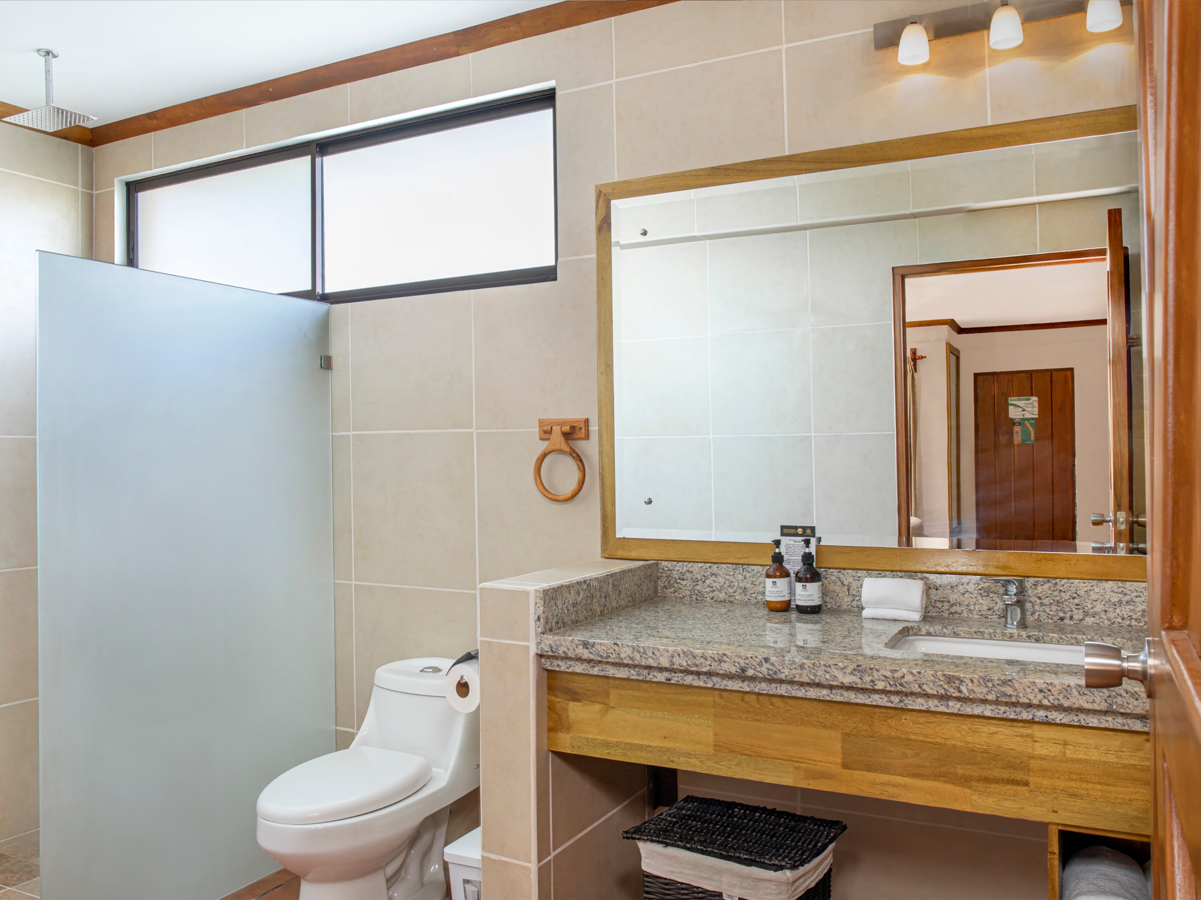 Modern bathroom with sink, mirror, toilet, and shower area with frosted glass.