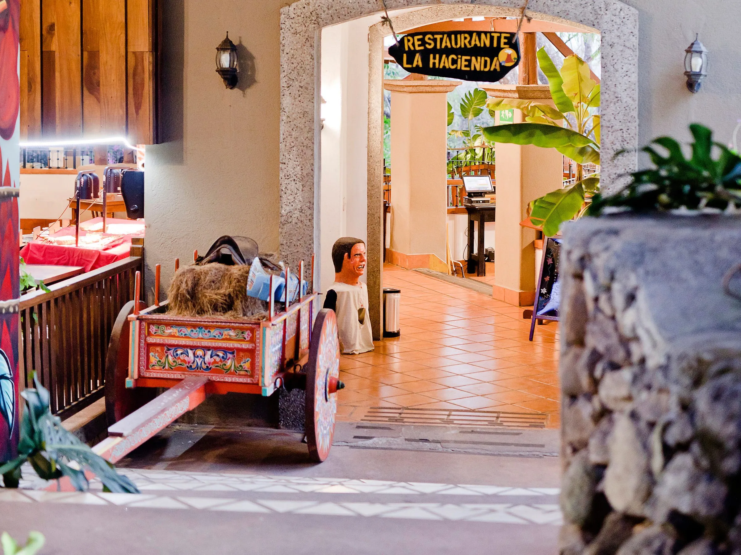 Entrance to Restaurante La Hacienda decorated with plants and a colorful cart.