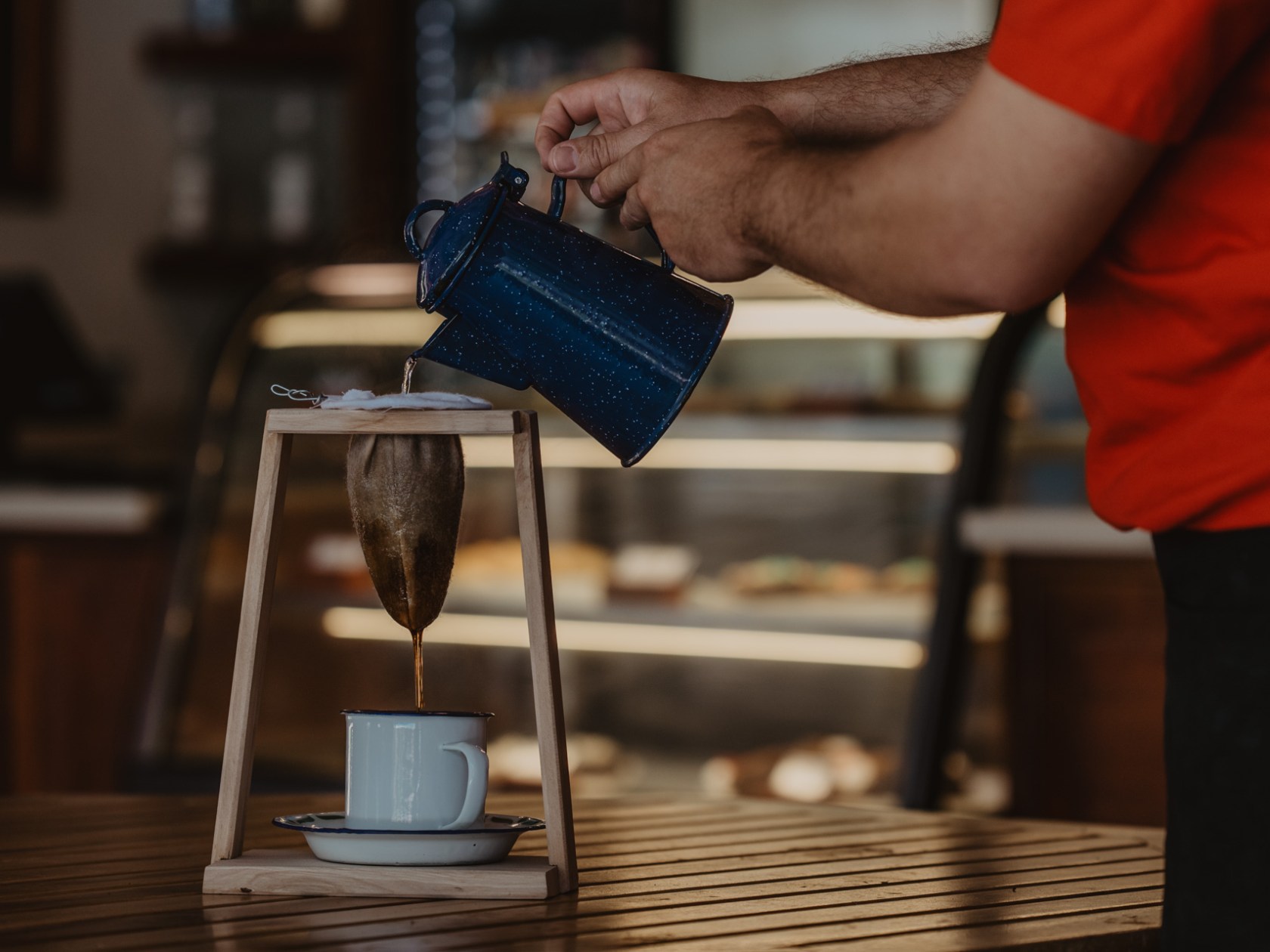 Person making coffee with a cloth filter and kettle over a cup