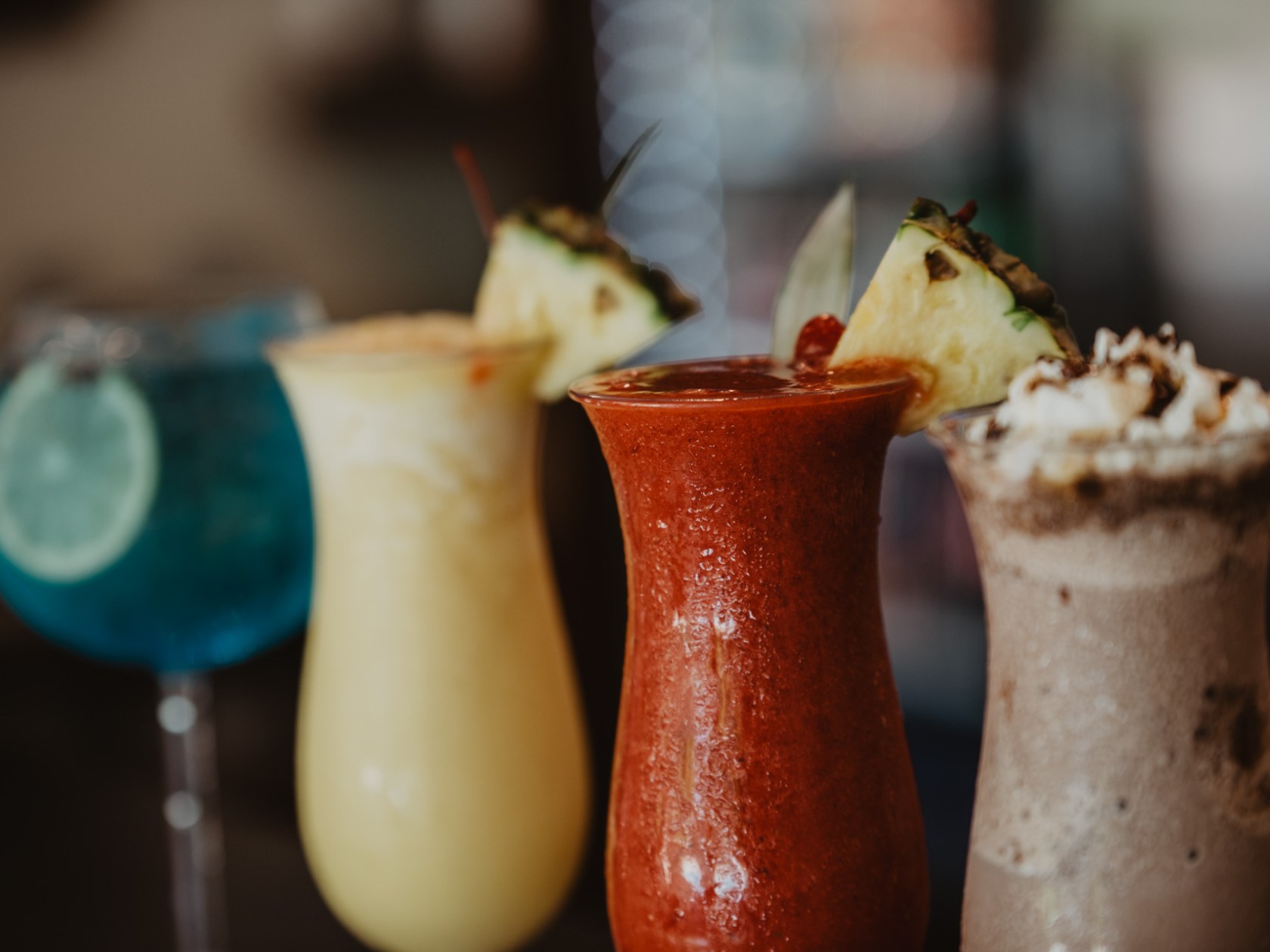 Assorted colorful cocktails with garnishes on a bar.