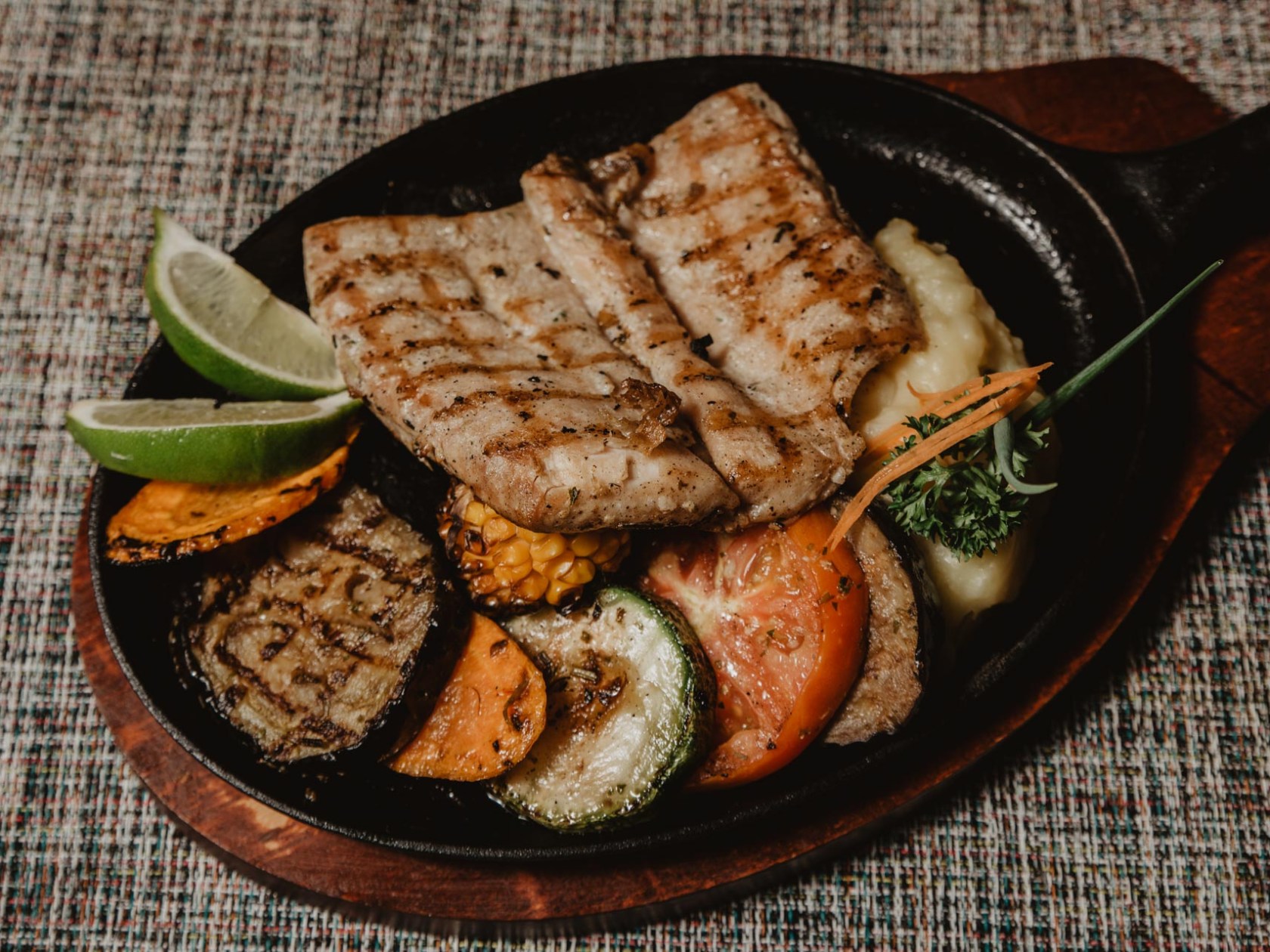 Grilled fish with vegetables and lime on a skillet.