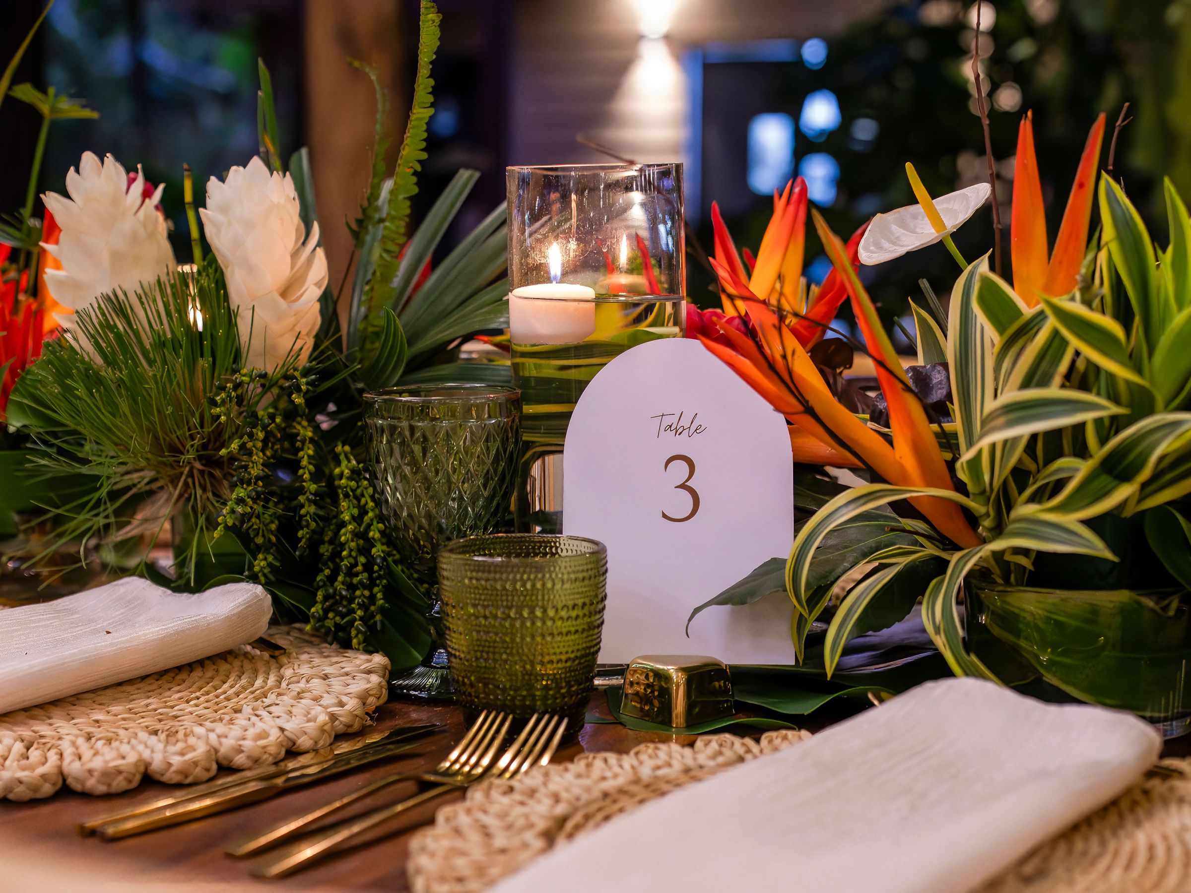 Table setting with tropical flowers, candle, and table number 3.