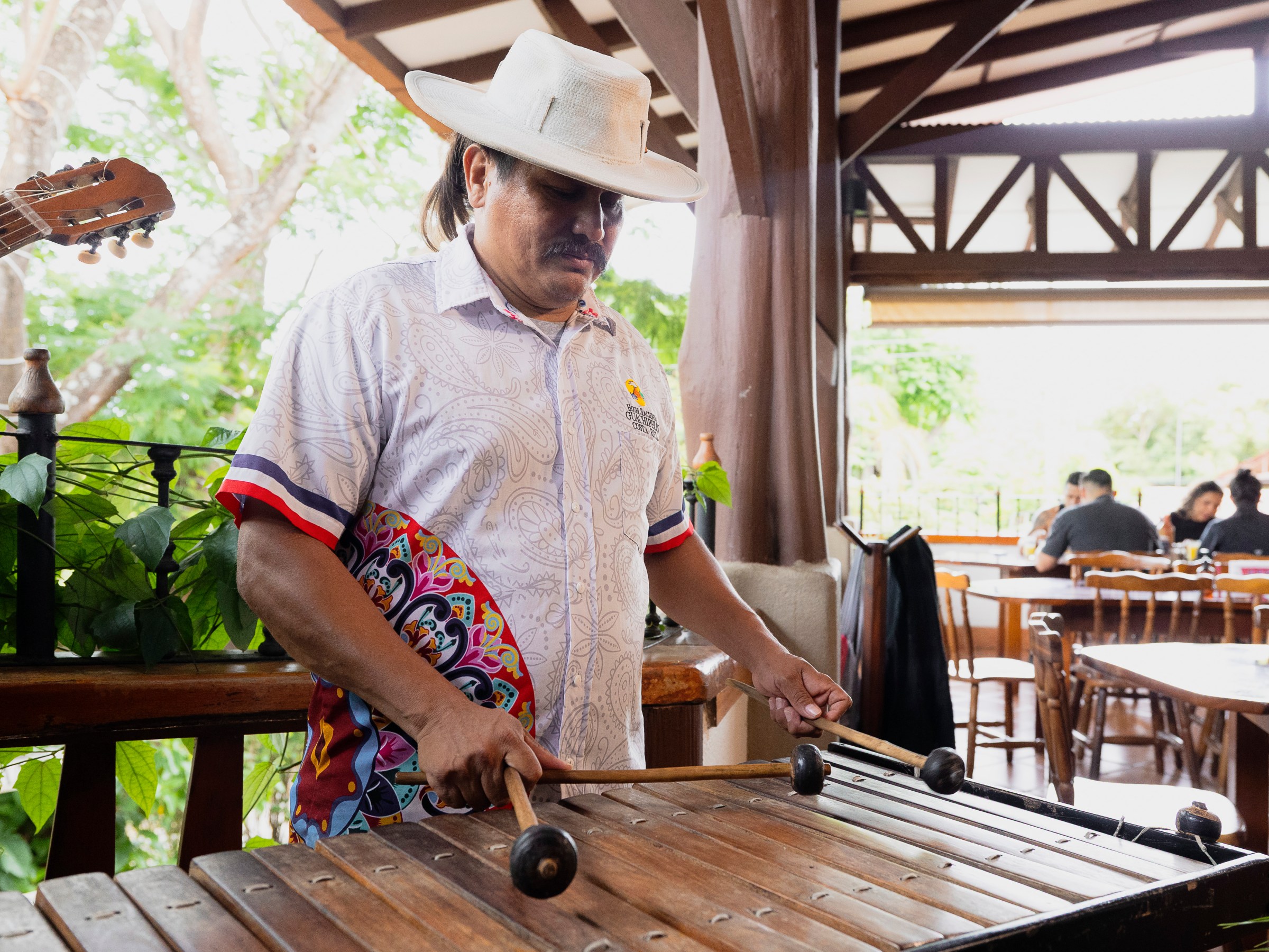 Man in hat playing marimba in a rustic indoor setting.