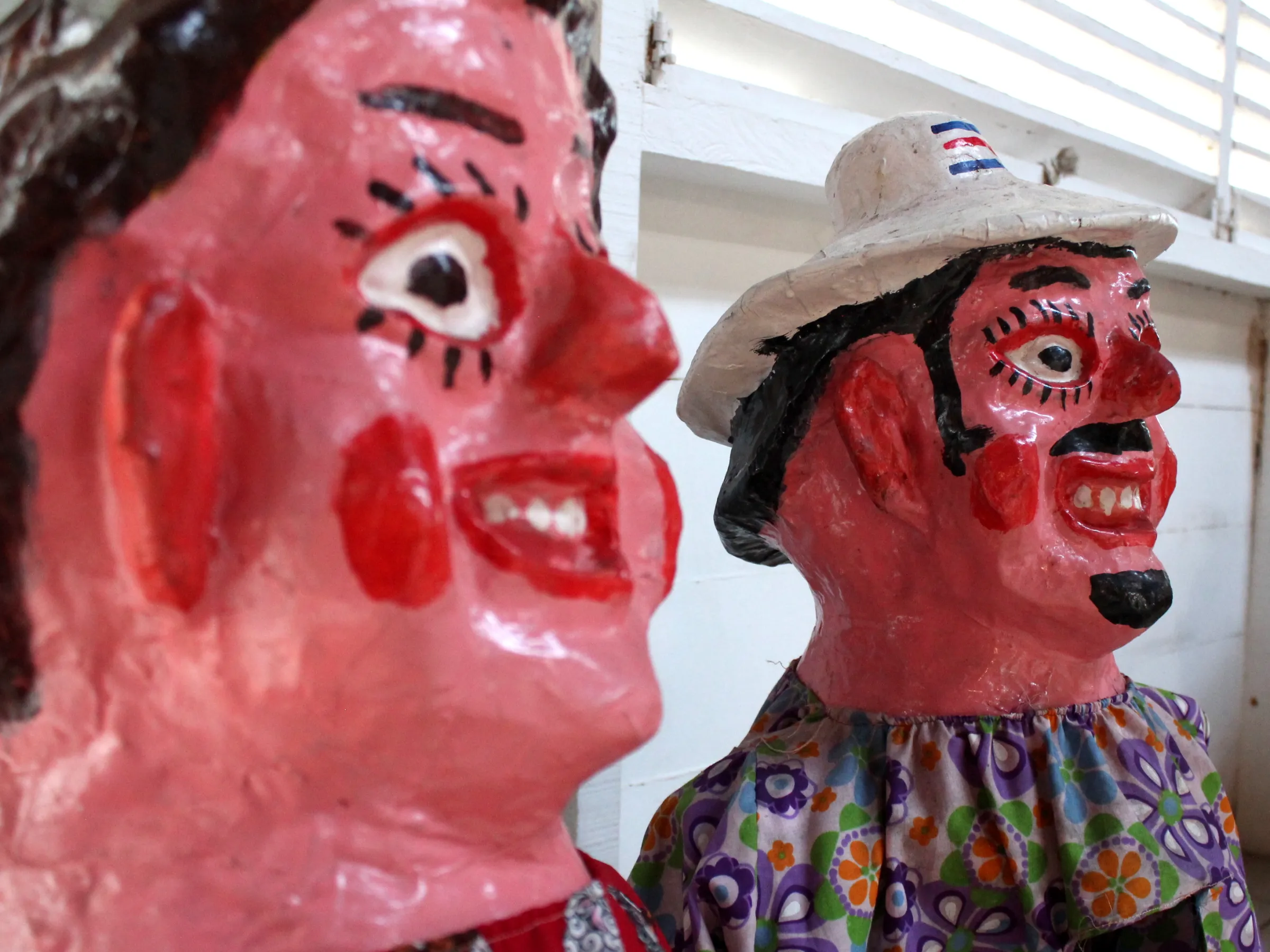 Two colorful papier-mâché figures with exaggerated facial features and festive clothing.