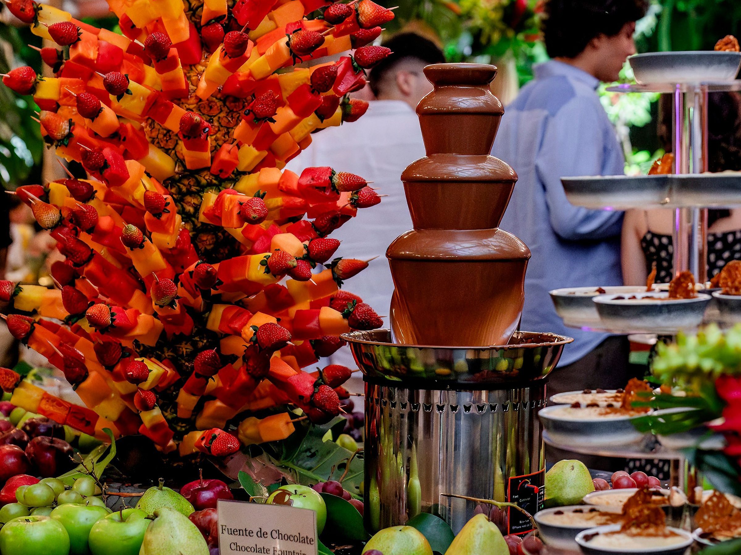 Fruit skewers and chocolate fountain on a decorated buffet table.