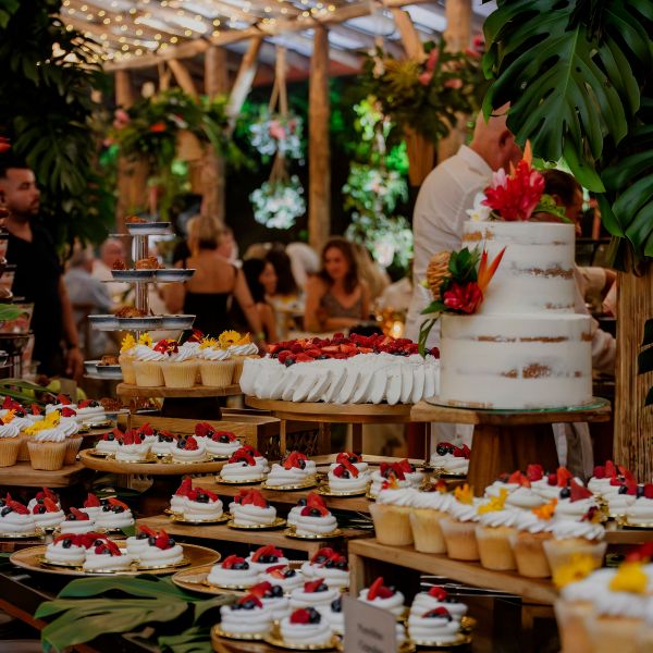Decorated dessert table with cakes and tarts at an outdoor event.