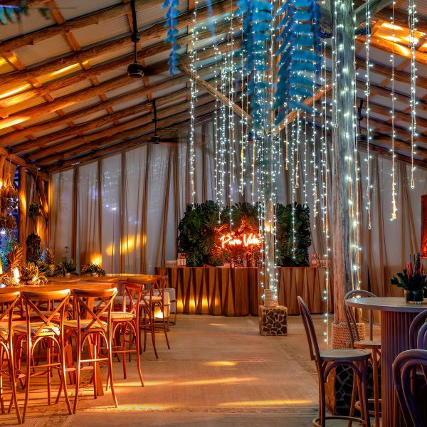 Decorated rustic event space with string lights and wooden furniture.