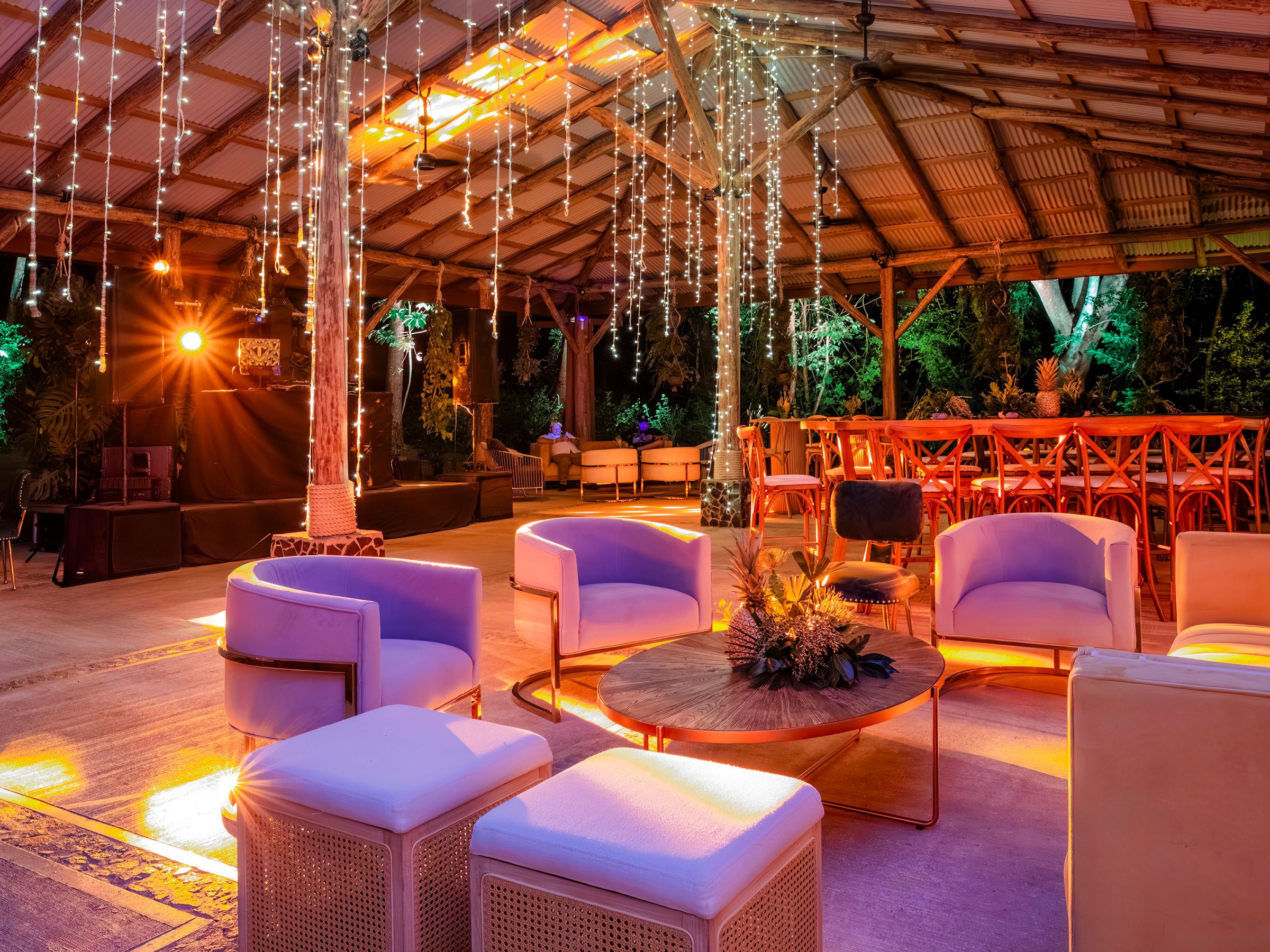 Cozy outdoor venue with modern seating, warm lights, and hanging decorations.