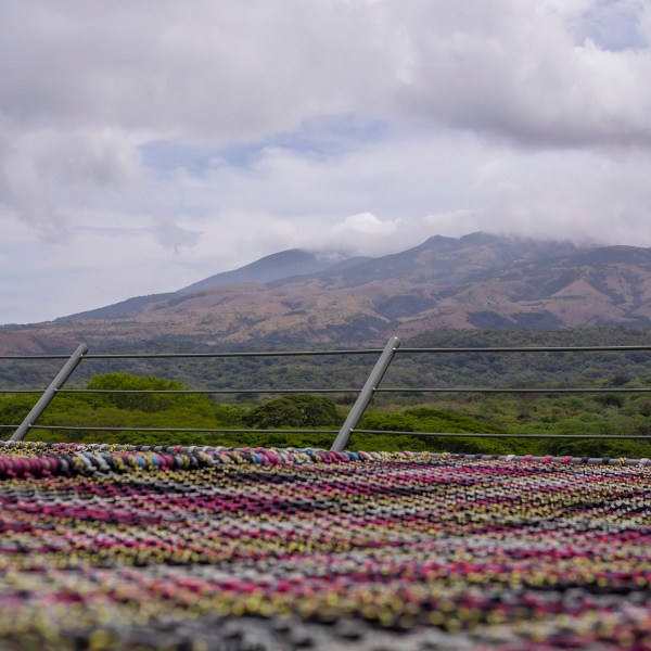 Colorful yarn on a rooftop with mountains and cloudy sky in background.