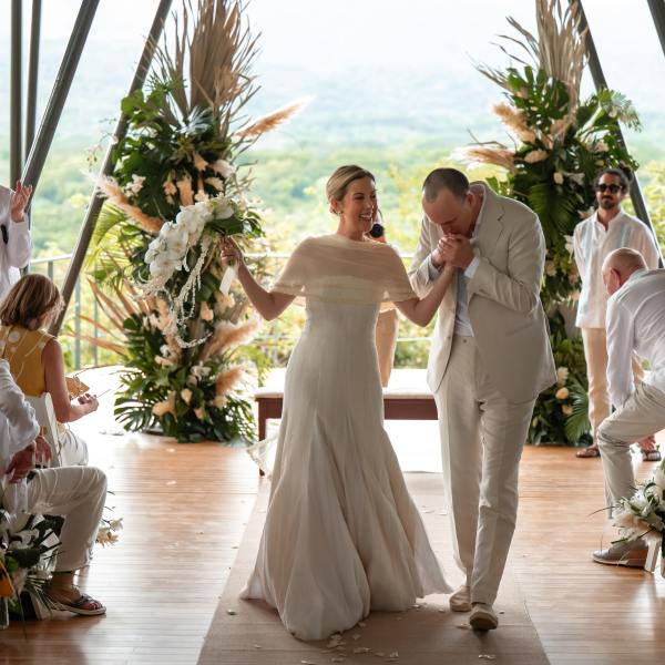 Bride and groom walk down aisle at outdoor wedding.
