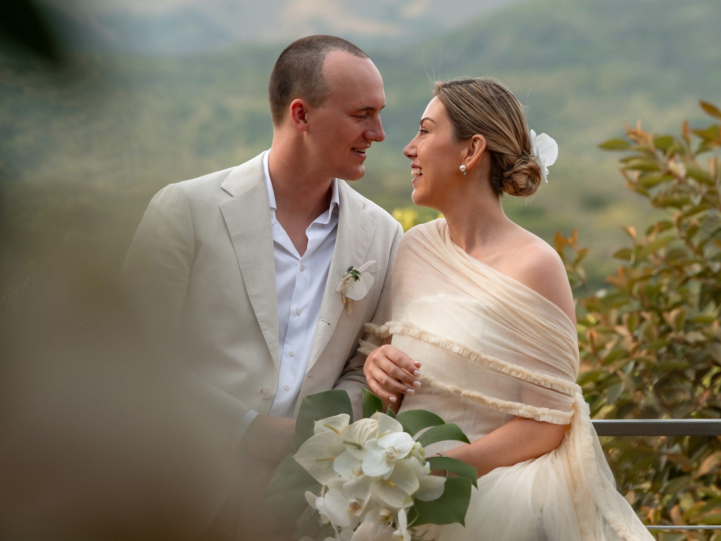 Bride and groom smiling at each other with mountains in the background.