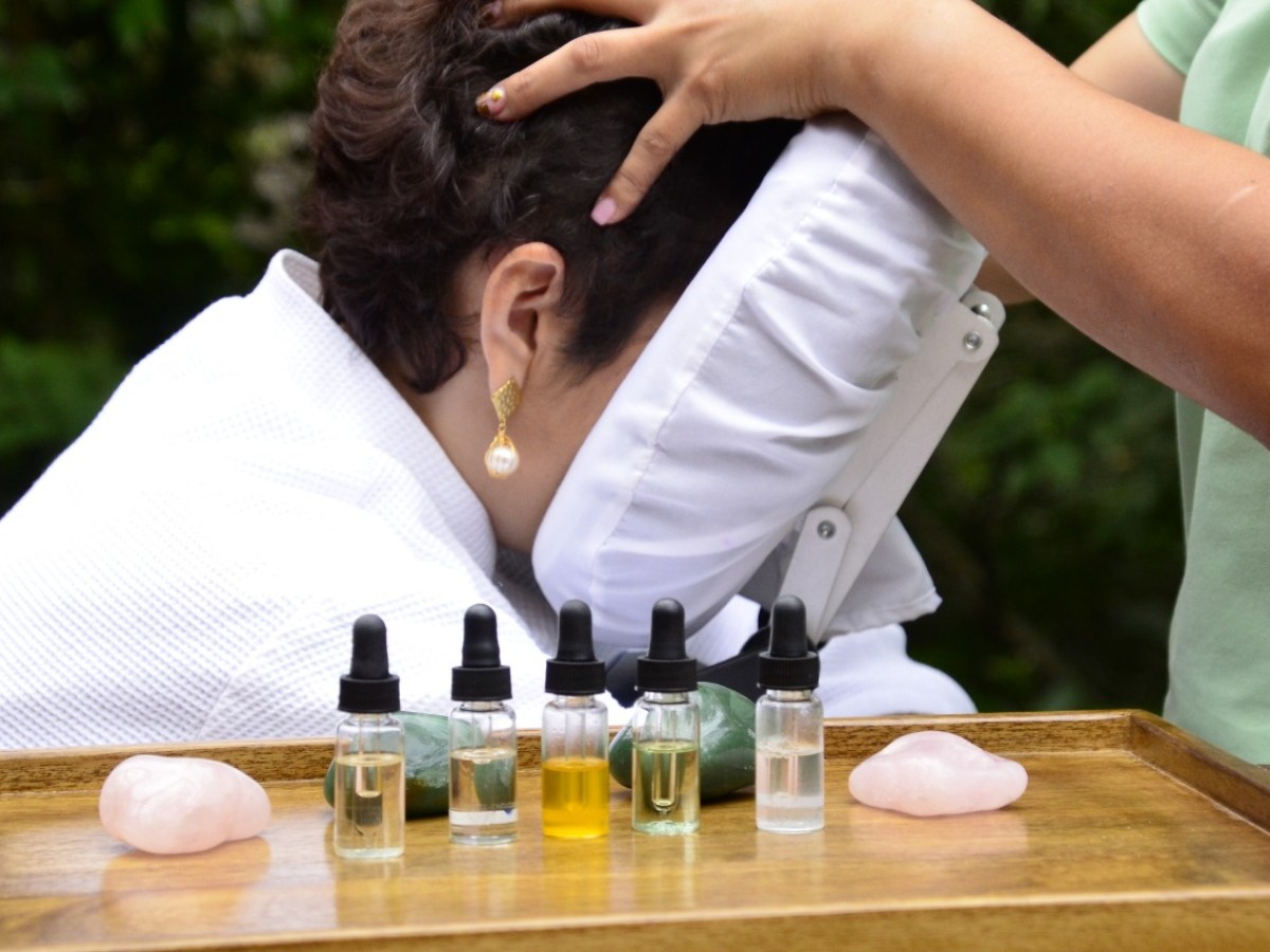 Person getting a massage with essential oils and crystals on a tray.