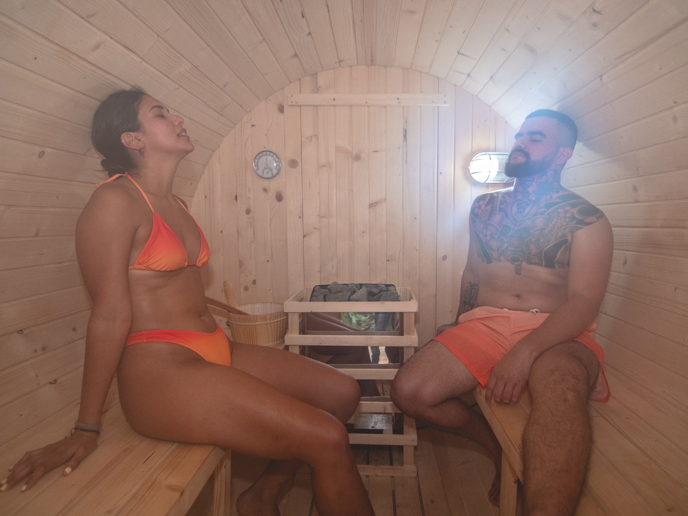 Two people relaxing in a wooden sauna.
