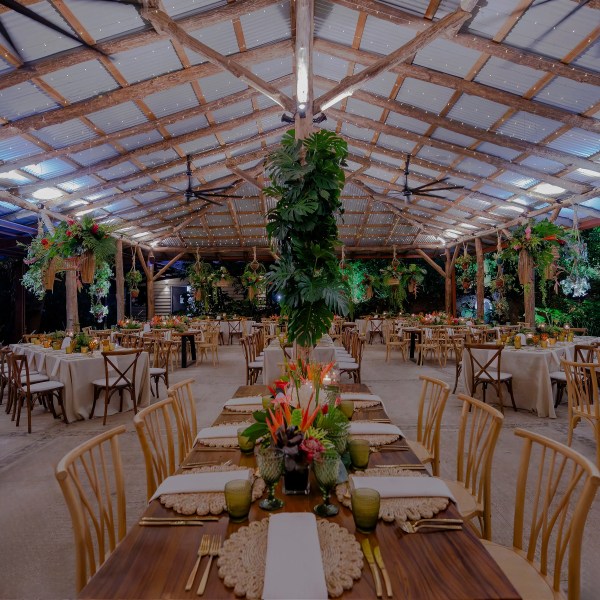Rustic outdoor dining area with wooden tables, chairs, and hanging plants.