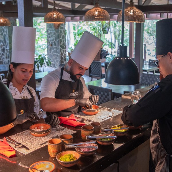 Three chefs preparing dishes in a professional kitchen.